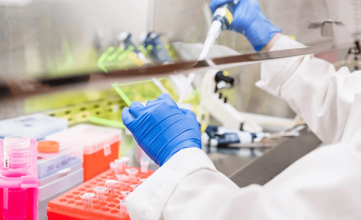 Gloved hands performing laboratory work under a fume hood for safe handling of chemical materials.