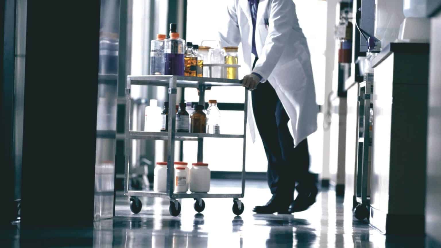 Person pushing a cart through a laboratory while transporting equipment and materials.