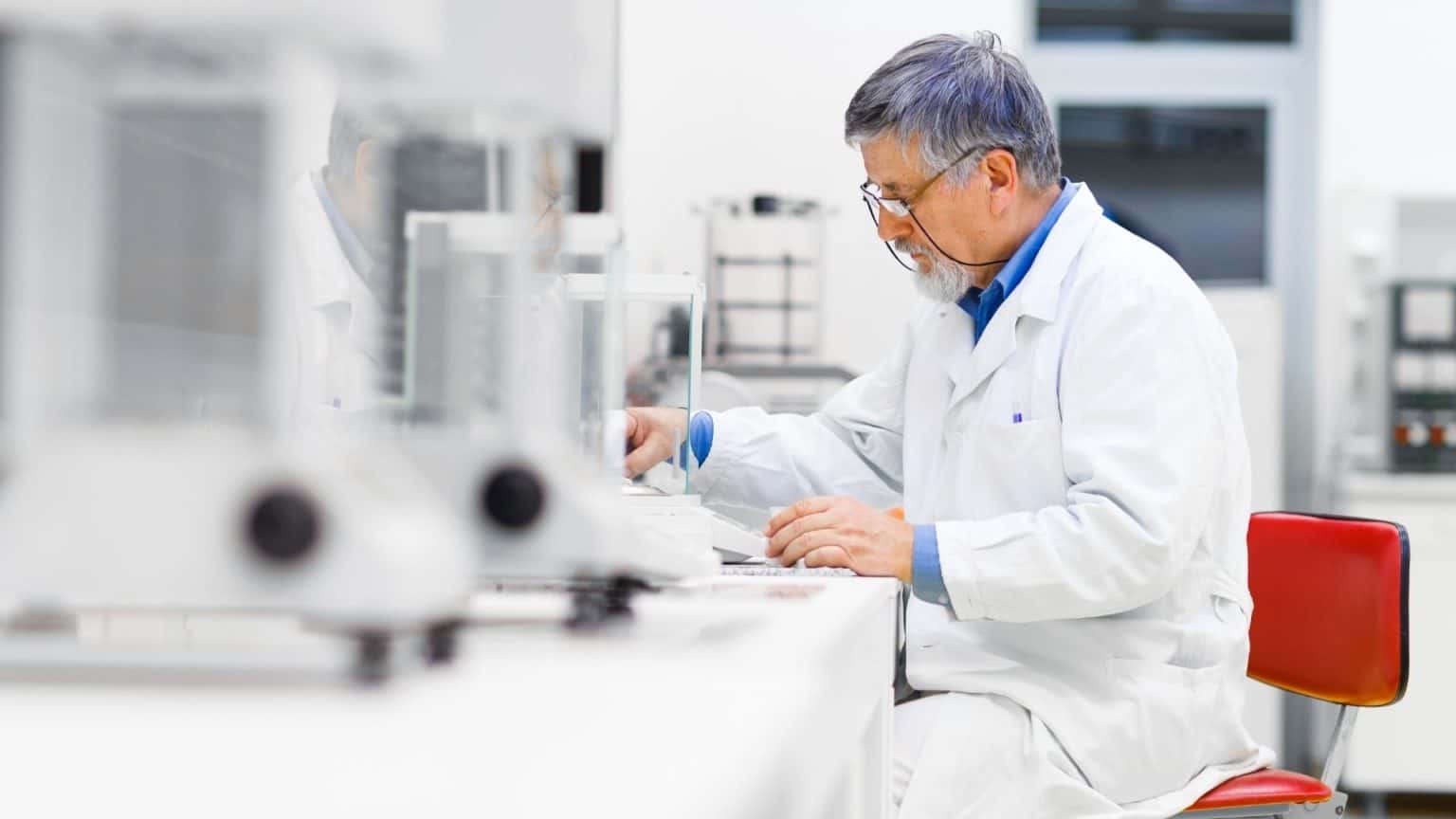 Man seated at a laboratory bench engaged in scientific work.